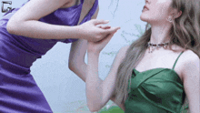 a woman in a purple dress holds another woman 's hand
