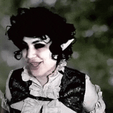 a woman with black hair and elf ears is wearing a black vest and a white shirt .