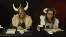 a woman in a viking helmet sits at a table with a name tag that says daniel