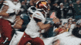 a football player with a w on his helmet is being tackled by another player
