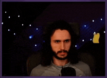 a man with long hair and a beard is sitting in front of a microphone and making a funny face
