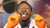 a man with glasses and orange gloves is holding a tooth in his mouth .