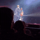 a man in a white shirt is walking on a stage with a woman behind him