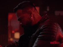 a man with a beard is wearing a black leather jacket with the words black brothers on it