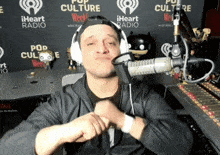 a man wearing headphones stands in front of a microphone in front of a wall that says pop culture
