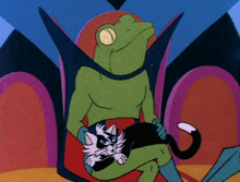 a green frog is holding a black and white cat in his lap