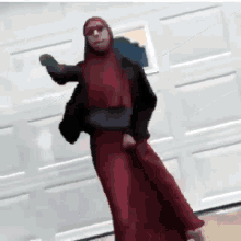 a woman in a red dress and sunglasses is dancing in front of a garage door