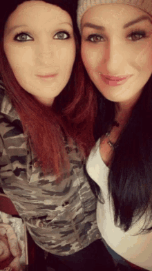 two women posing for a picture with one wearing a camouflage jacket