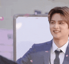 a man in a suit and tie is shaking hands with another man in front of a whiteboard .