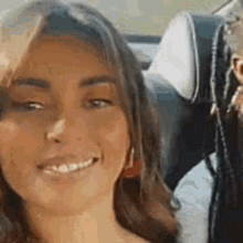 a close up of a woman sitting in a car smiling at the camera .
