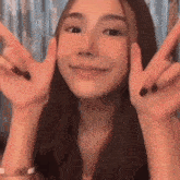 a close up of a woman making a peace sign with her hands