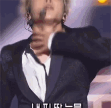 a man in a suit is singing into a microphone while wearing headphones ..
