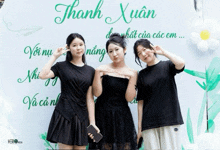 three girls pose in front of a wall that says thanh xuan