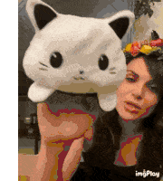 a woman is holding a white stuffed cat in her hand .