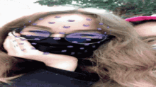 a woman wearing glasses and a mask with purple dots on her forehead