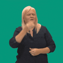 a woman wearing a blue shirt is making a hand gesture