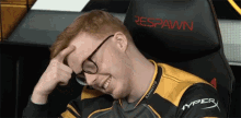 a man wearing glasses is sitting in a chair that says respawn on it