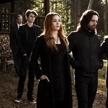 a group of people are walking in a line in the woods .