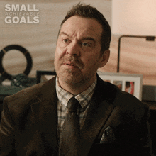 a man in a suit and tie with the words small achievable goals on the bottom