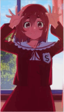 a girl in a red dress is standing in front of a window with her hands on her head .