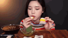 a woman is sitting at a table eating a piece of food