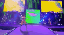 a female wrestler is dancing on a stage in front of a giant screen .