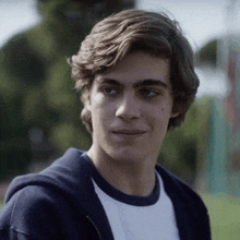 a young man wearing a white t-shirt and a blue hoodie