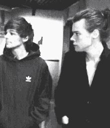 a black and white photo of two young men standing next to each other .