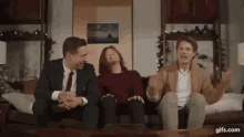 a group of people are sitting on a couch laughing and having fun .