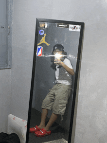 a person taking a selfie in front of a mirror with stickers on the wall including one that says red club
