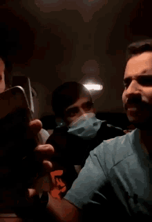 a man wearing a face mask is sitting in a car with other people