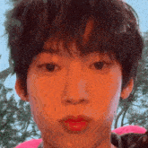 a close up of a young man 's face with a pink float in the background .