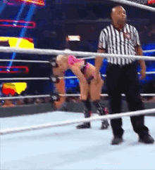 a referee is standing next to a wrestler in a wrestling ring .