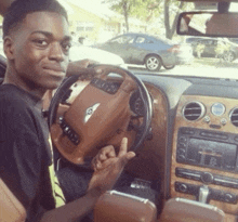 a man is sitting in a bentley car and giving the middle finger