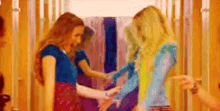 a group of women are standing next to each other in a hallway holding hands .
