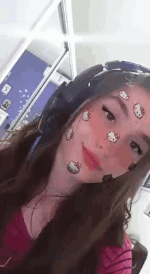 a girl wearing headphones and a hello kitty face filter .