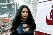 a woman in a superhero costume is standing in front of a white van with the letter l on it .