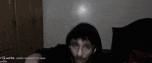 a man wearing a hooded jacket and headphones is sitting in a dark room with the words studio malaych 10 nass visible