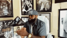 a man wearing a hat that says rob is sitting in front of framed pictures