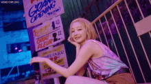 a woman is sitting in front of a sign that says grand opening .