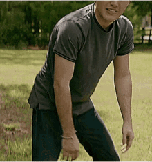 a man in a gray shirt and blue jeans is standing in the grass