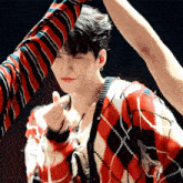 a man in a plaid sweater is making a heart sign