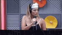 a woman wearing headphones and a hat with the number 805 on it is singing into a microphone