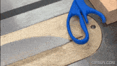 a pair of scissors cutting a piece of wood on a table saw