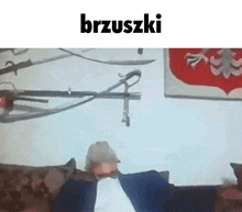 a man is sitting on a couch in front of a wall with swords hanging from it and the word brzuszki on the top