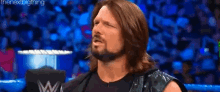 a wrestler with long hair and a beard is standing in a ring .