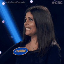 a woman applauds while wearing a badge that says ' familyfeud canada ' on it