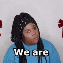 a woman with dreadlocks wearing a bandana and a blue shirt says we are