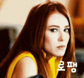 a woman with long red hair is wearing a yellow shirt and looking at the camera