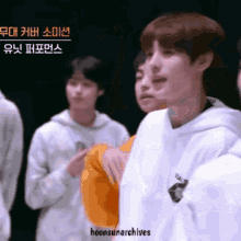 a man in a white hoodie is standing next to another man in an orange hoodie